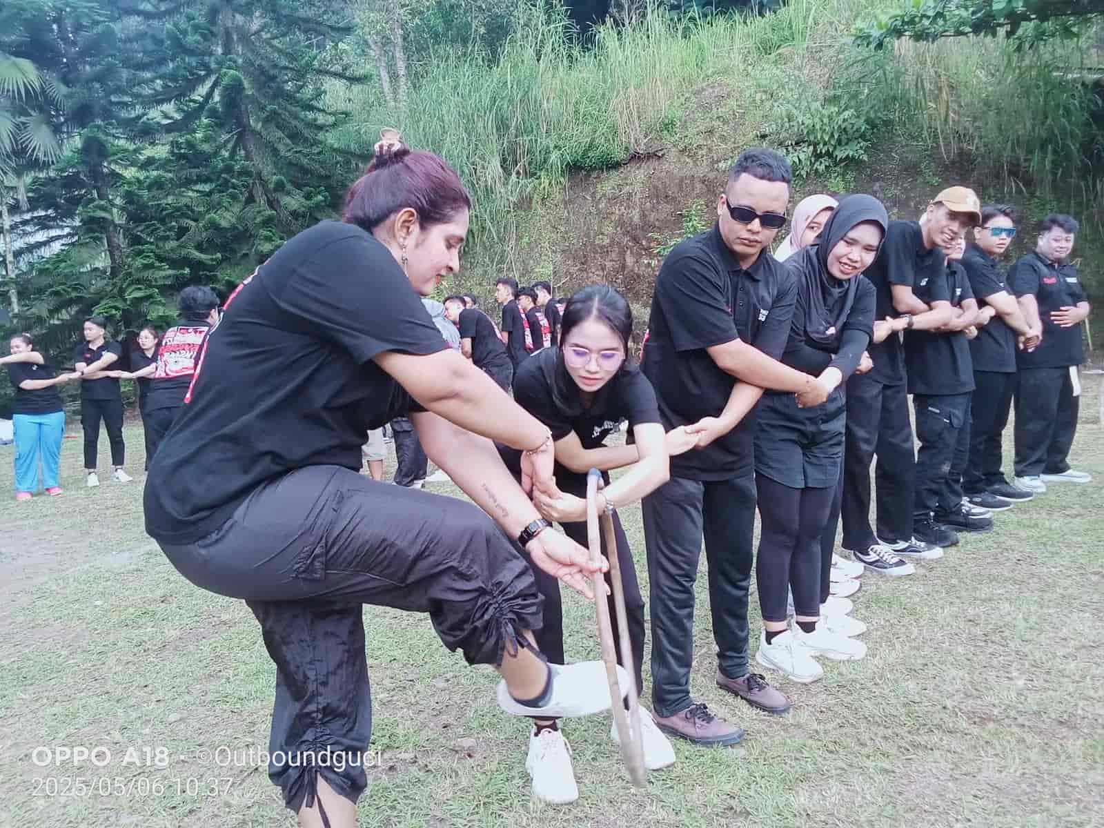 Tim peserta team building bekerja sama dalam kegiatan di alam terbuka Guci